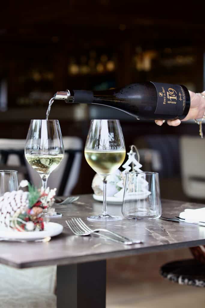 table dressée pour Noël, deux verres de vin, bouteille de vin blanc servie